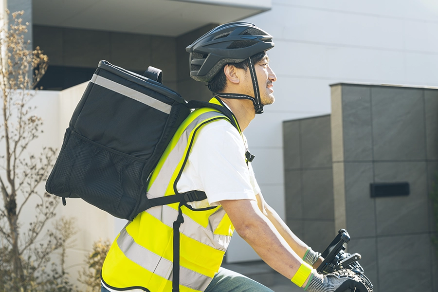 Man in yellow safety vest riding a bike with a backpack on